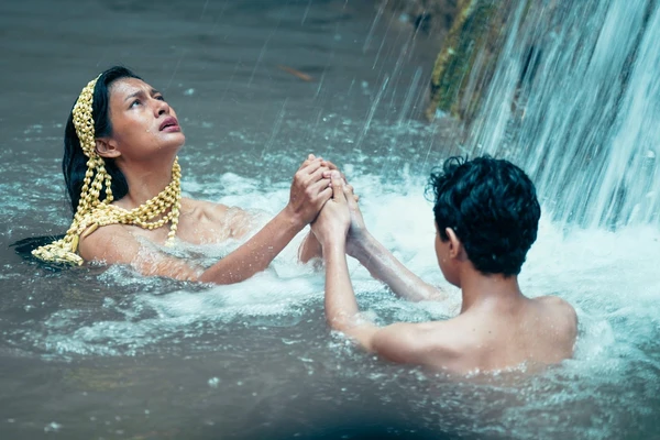 Two characters in water at waterfall in "Gowok: Javanese Kamasutra".