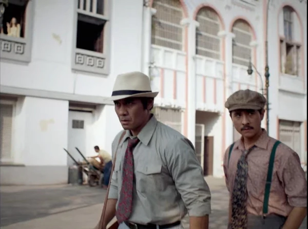 Two men walk on a street in the chaotic city of "Perang Kota".