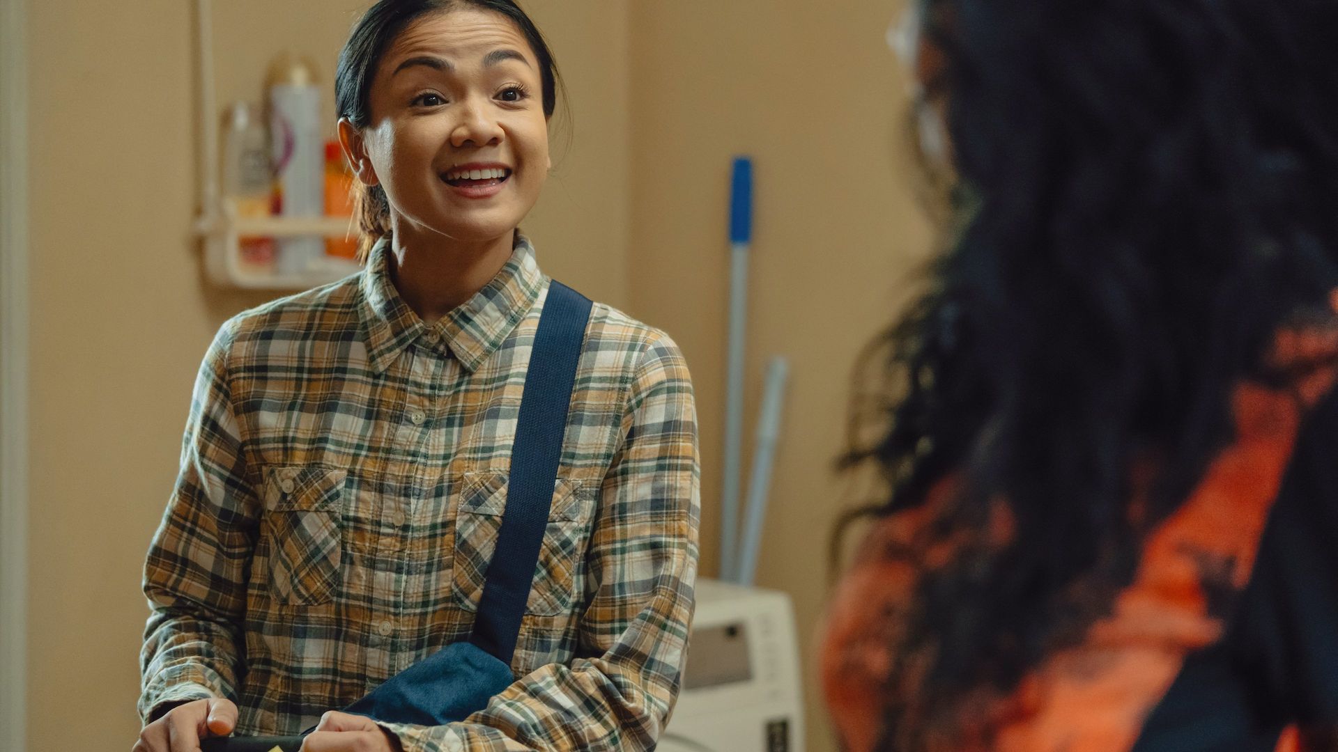 A woman smiles brightly in a room in Ratu Ratu Queens: The Series.