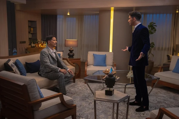 Two men engage in a conversation in a well - furnished living room in The Most Beautiful Girl in the World.